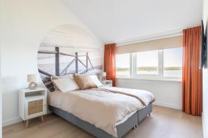 a bedroom with a large bed and a window at Beachhouse Wadmeer - Aan het water in Wieringerwerf