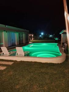 una piscina verde por la noche con sillas alrededor en Casa de Campo Villa Azul Cañete, en Imperial
