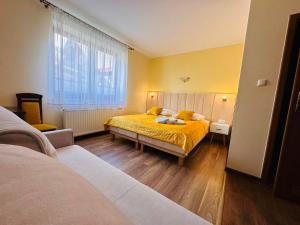 Un dormitorio con 2 camas y una ventana con paredes amarillas. en Górska Przystań SPA, en Krynica-Zdrój