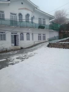 a snow covered driveway in front of a white building at Marry House in Murree