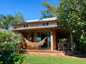 a house with a hammock on the front of it at Fazenda do Rosa in Praia do Rosa