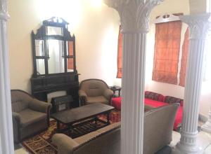 a living room with chairs and a table and columns at Marry House in Murree