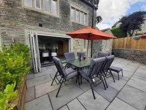 eine Terrasse mit einem Tisch mit Stühlen und einem Sonnenschirm in der Unterkunft Beautiful countryside cottage, sleeps 6, dogs welcome in Halifax