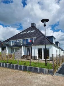 een wit huis met een zwart dak bij Vakantie vieren aan het Sneekermeer in Offingawier