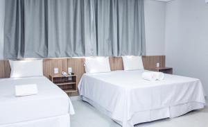 two beds in a hotel room with white sheets at Hotel Solar Paulista in Sao Paulo