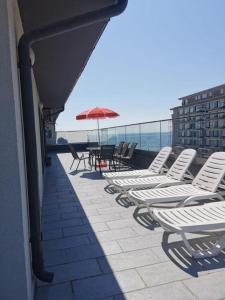 a row of chairs and an umbrella on a balcony at Korallia Penthouse in Mamaia Nord