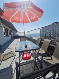 a table and chairs with an umbrella on a balcony at Korallia Penthouse in Mamaia Nord