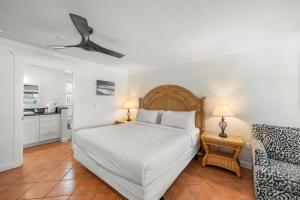 1 dormitorio con 1 cama blanca y 1 silla en Tropic Isle At Anna Maria Island Inn, en Bradenton Beach