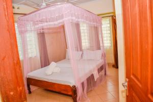 Schlafzimmer mit einem Himmelbett und rosa Vorhängen in der Unterkunft Karura and friends airbnb (affordable) in Ukunda