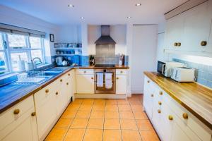 a kitchen with white cabinets and orange tile floors at Leam Terrace Escape in Leamington Spa