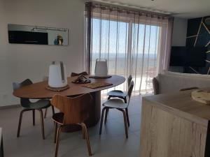 ein Wohnzimmer mit einem Tisch und Stühlen sowie Meerblick in der Unterkunft Luxueux appartement bord de plage, terrasse et spa in Valras-Plage