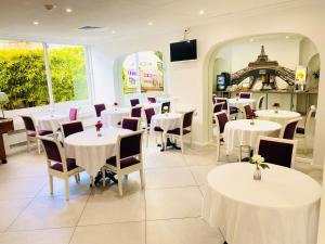 a dining room with white tables and chairs at H&ocirc;tel D'orsay in Orsay