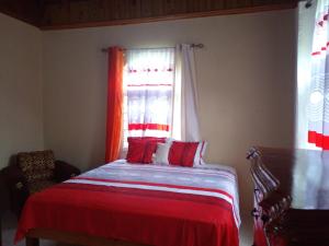 Un dormitorio con una cama con sábanas rojas y una ventana en The Kozy Kotch, en Montego Bay