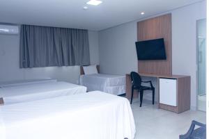 a hotel room with two beds and a desk and a tv at Hotel Solar Paulista in São Paulo
