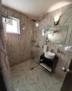 uma casa de banho com um lavatório e uma cabina de duche em vidro. em Luxury Haven. Harmony Suites. em Vrindavan
