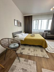 ein Schlafzimmer mit einem Bett und einem Stuhl darin in der Unterkunft Студия в теплых тонах, Эксклюзив in Almaty