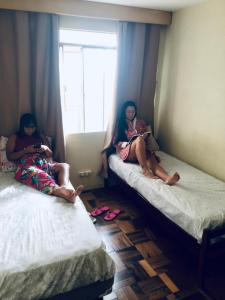 庫里奇巴的住宿－Vicz Palace Hotel，两名妇女坐在房间里的床上