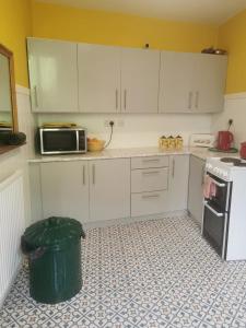 eine Küche mit weißen Schränken und einem Mülleimer in der Unterkunft Freedom park villas room 1 in Plymouth