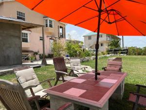 聖菲利普的住宿－ABBE Garden Hideaway，一把橙色的遮阳伞,坐在桌子上,摆放着椅子