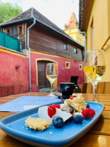 a blue plate of food and two glasses of wine at Pensiune Citadela Sighisoara in Sighişoara