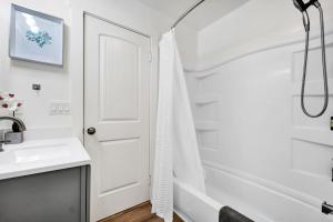 a white bathroom with a shower and a sink at Retro Cottage, Hot Tub, Putting Green, walk to all in Thousand Oaks +40 photos