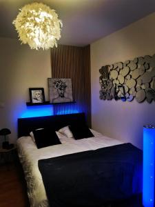 a bedroom with a large bed with a blue light at L'atelier de Jane in Sennecey-lès-Dijon
