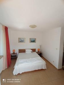 a bedroom with a white bed and two tables at Guesthouse Kolevi in Lozenets