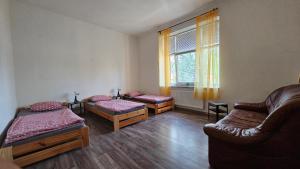um quarto com três camas e um sofá e uma janela em Ubytovaní U Dvora em Bohumín