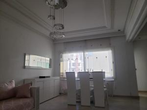 ein Wohnzimmer mit weißen Wänden sowie einem Tisch und Stühlen in der Unterkunft Luxurious apartment in Fès