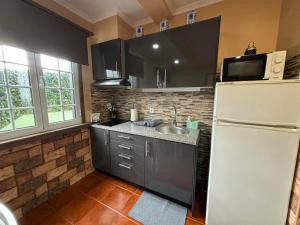 a kitchen with a white refrigerator and a sink at Casa da Vista- Eirinha in Furnas