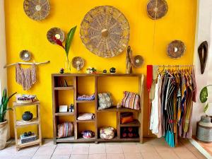 a room with a yellow wall with shelves and umbrellas at Hotel Casa Mixteca in Zipolite