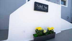 a sign on the side of a building with flowers at Saint Sin Suites - Adults Only in Imerovigli