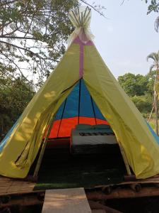 een gele en blauwe tent met een bed erin bij Clandestino Hostal in Gigante