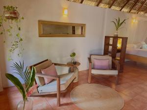 a living room with two chairs and a bed at Hotel Casa Mixteca in Zipolite