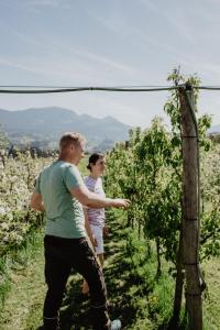 two men standing in a vineyard pointing at something at 4 Sterne Ferienwohnung Hochries in Rohrdorf