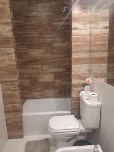 a bathroom with a white toilet and a bath tub at Tu Refugio 3 - Monoambiente/Loft cerca del parque in Santiago del Estero