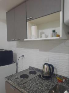 a kitchen counter with a tea kettle on a stove at Tu Refugio 3 - Monoambiente/Loft cerca del parque in Santiago del Estero +1 photo
