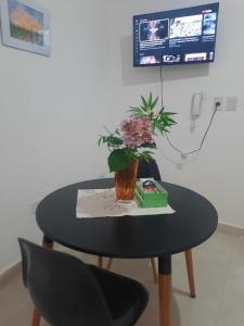 a black table with a vase of flowers on it at Tu Refugio 3 - Monoambiente/Loft cerca del parque in Santiago del Estero