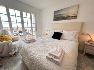Un dormitorio con una cama blanca con toallas. en Nuestro Atico con vistas al Mar Terraza, Piscina y Parking, en Málaga