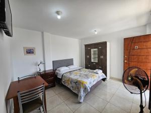 a bedroom with a bed and a desk and a chair at Hospedaje Las Parraz in Ica
