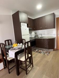 eine Küche mit einem Tisch mit Stühlen und einem Kühlschrank in der Unterkunft Apartamento El Viaducto en Redondela in Redondela