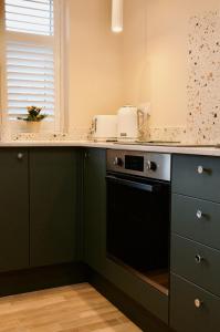 uma cozinha com armários verdes e uma máquina de lavar louça preta em The Sunset Nook em Copdock
