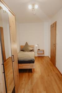 a small bedroom with a bed and a wooden floor at Ferienwohnung/Arbeiterwohnung Kampenwand in Rohrdorf