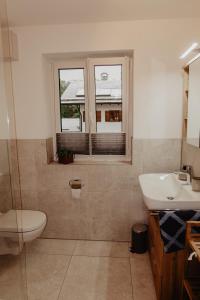 baño con lavabo y aseo y ventana en Ferienwohnung/Arbeiterwohnung Kampenwand en Rohrdorf