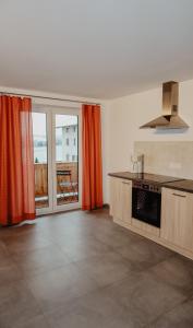 a kitchen with orange curtains and a view of a balcony at Ferienwohnung/Arbeiterwohnung Kampenwand in Rohrdorf