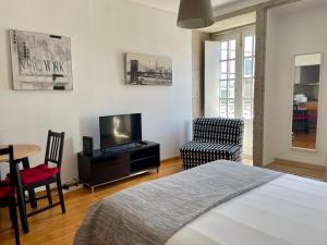 um quarto com uma cama, uma televisão e uma cadeira em Douro River Cozy Flats no Porto