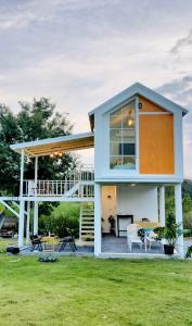 ein Haus mit einer Terrasse und einer Liegewiese in der Unterkunft บ้านไร่ฟ้าสวยวังน้ำเขียว Little House in Ban Khlong Ta Sang