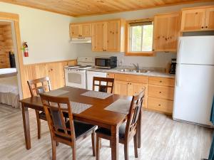 cocina con mesa de madera y nevera blanca en Hidden Acres Cottages, en Cavendish