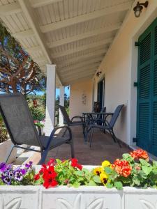a patio with chairs and flowers on a porch at HeleNik Holiday House in Halikounas