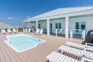 une terrasse avec une piscine et des chaises ainsi qu'un bâtiment dans l'établissement Bienville Beach Compound, à Dauphin Island